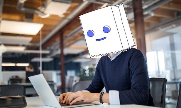 Blogpost-image 一个匿名的男人，头上顶着一个带插图的包，放在他的笔记本电脑后面